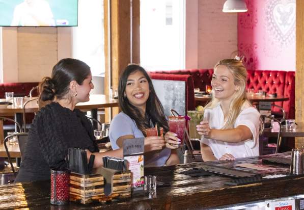 3 women smiling with cocktails. girls night