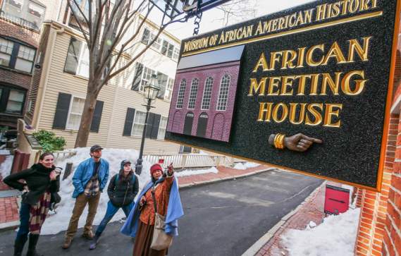4 people looking at a sign that reads "Museum of African American History; African Meeting House."