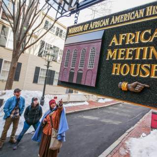 4 people looking at a sign that reads "Museum of African American History; African Meeting House."