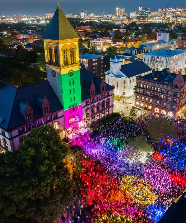 Aerial view at night of the Cambridge Dance Party, building and crowd illuminated by colorful lights