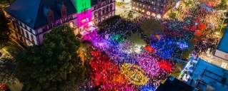 Aerial view at night of the Cambridge Dance Party, building and crowd illuminated by colorful lights