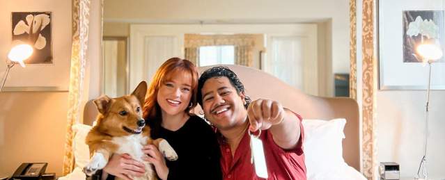 Couple with dog on hotel bed