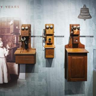 Antique photo of a girl holding an old wooden telephone